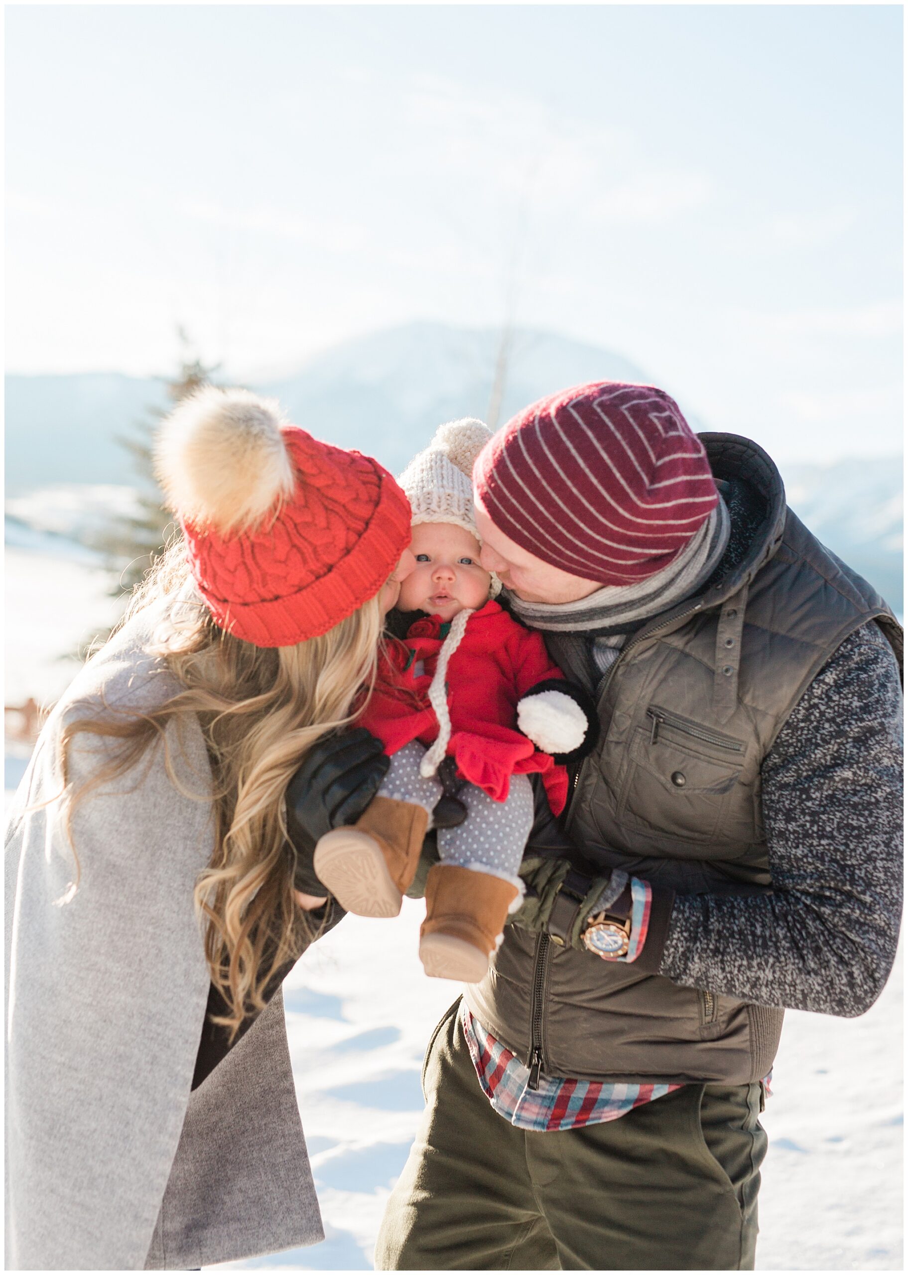 mom and dad kissing the cheek of their baby during their winter family photos in Breckenridge