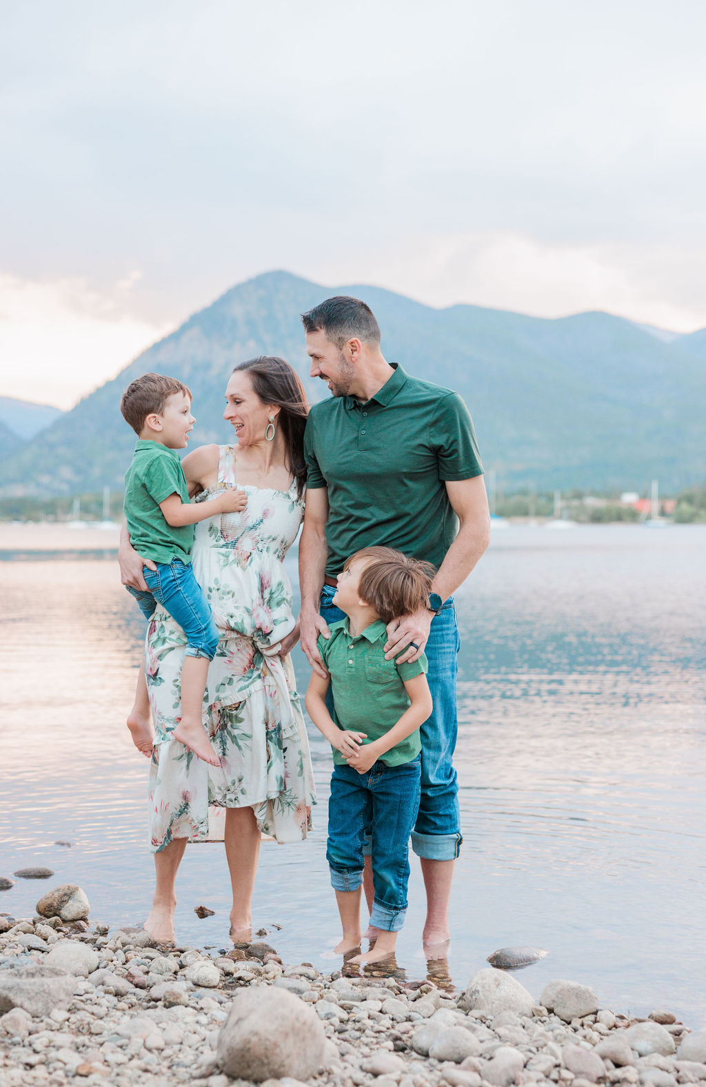 A family of 4 plays and giggles on an alpine lake at sunset