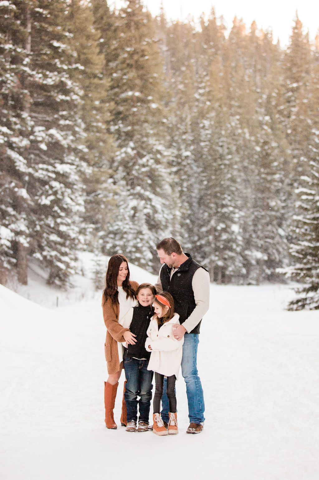 Family of four huddled together and smiling in the snow during Breckenridge Winter Activities