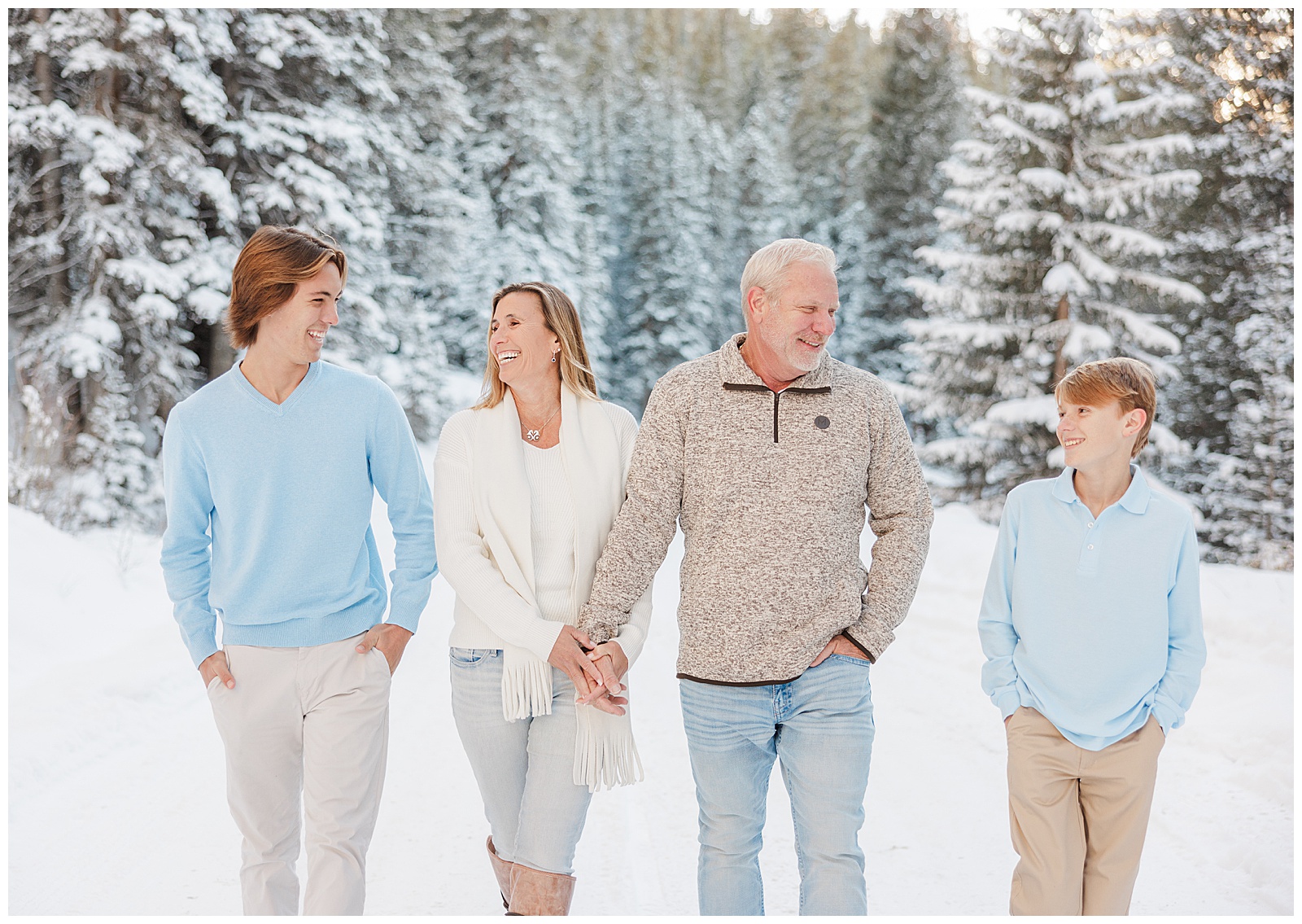 A family of four is walking together in the snow covered landscape, smiling