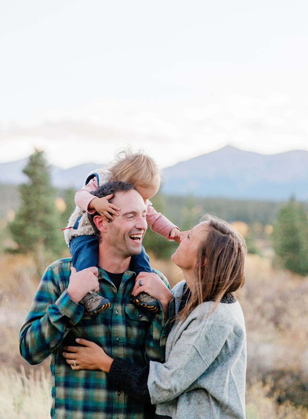 A baby girl sits on dad's shoulders while on a hike in the mountains after visiting a daycare in breckenridge