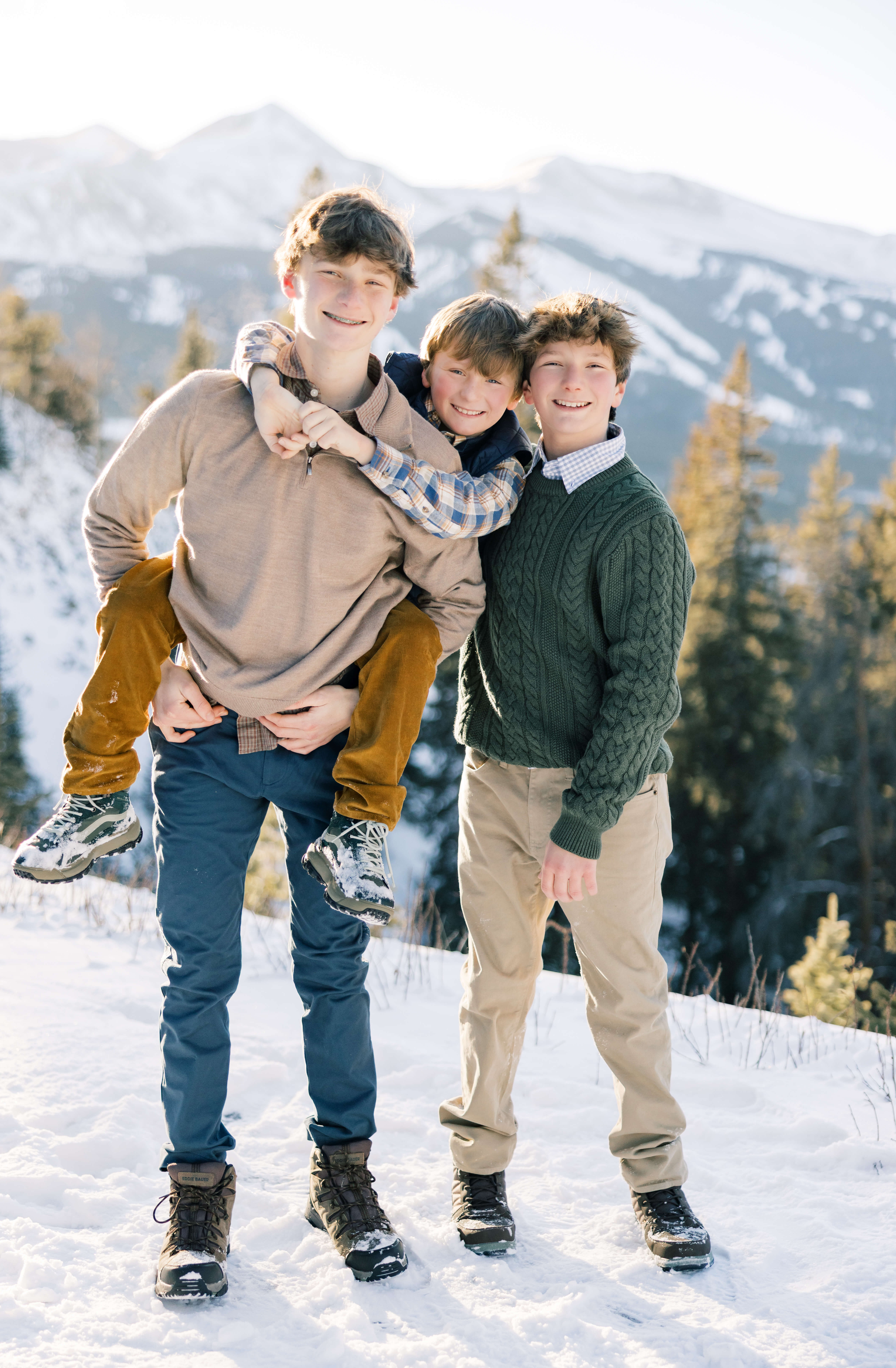 Three young brothers hang on each other while hiking in the snow on a mountain before heading to Apres Ski in Breckenridge