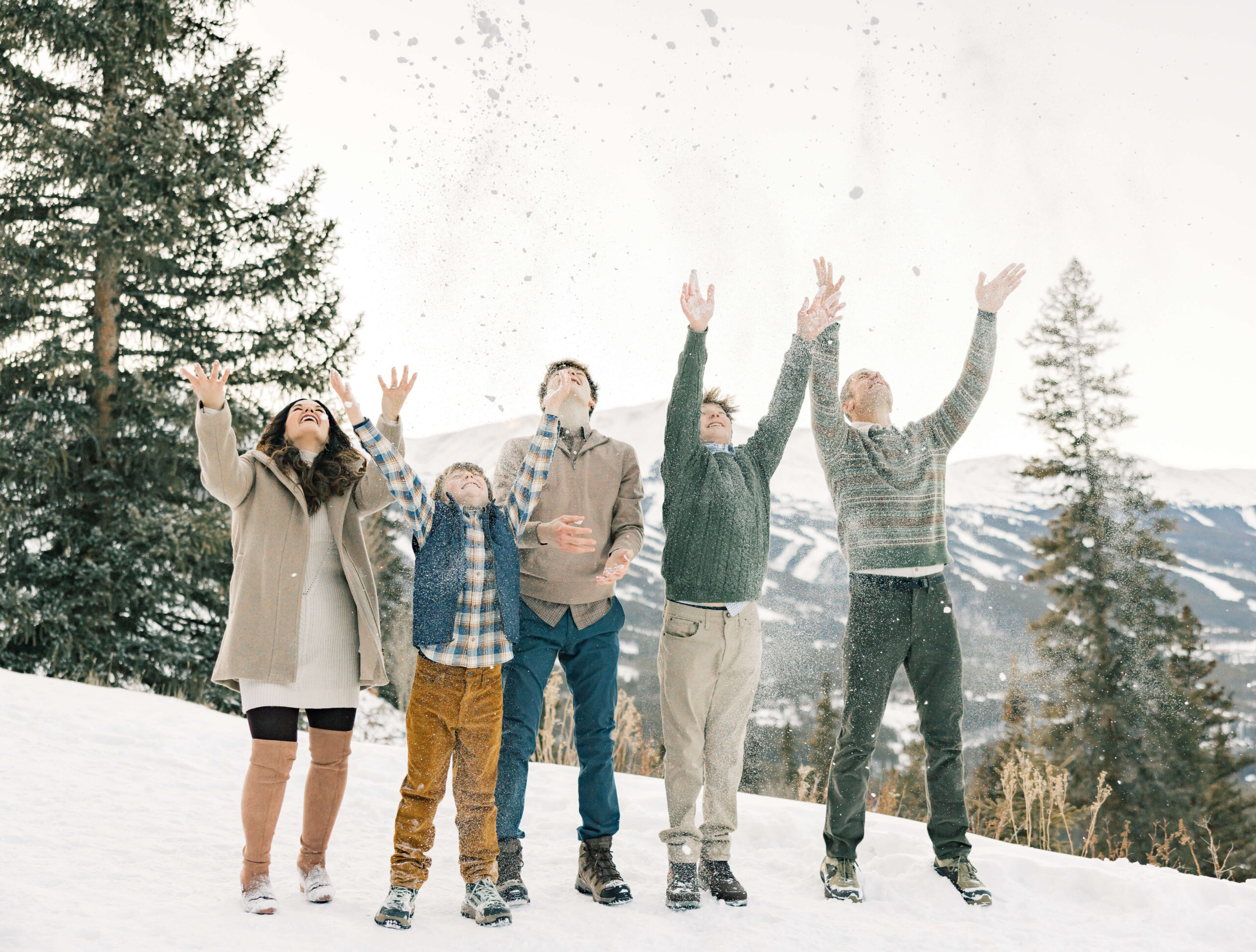 A family of 5 with three teen sons toss snow in the air on a mountain before heading to an Apres Ski in Breckenridge