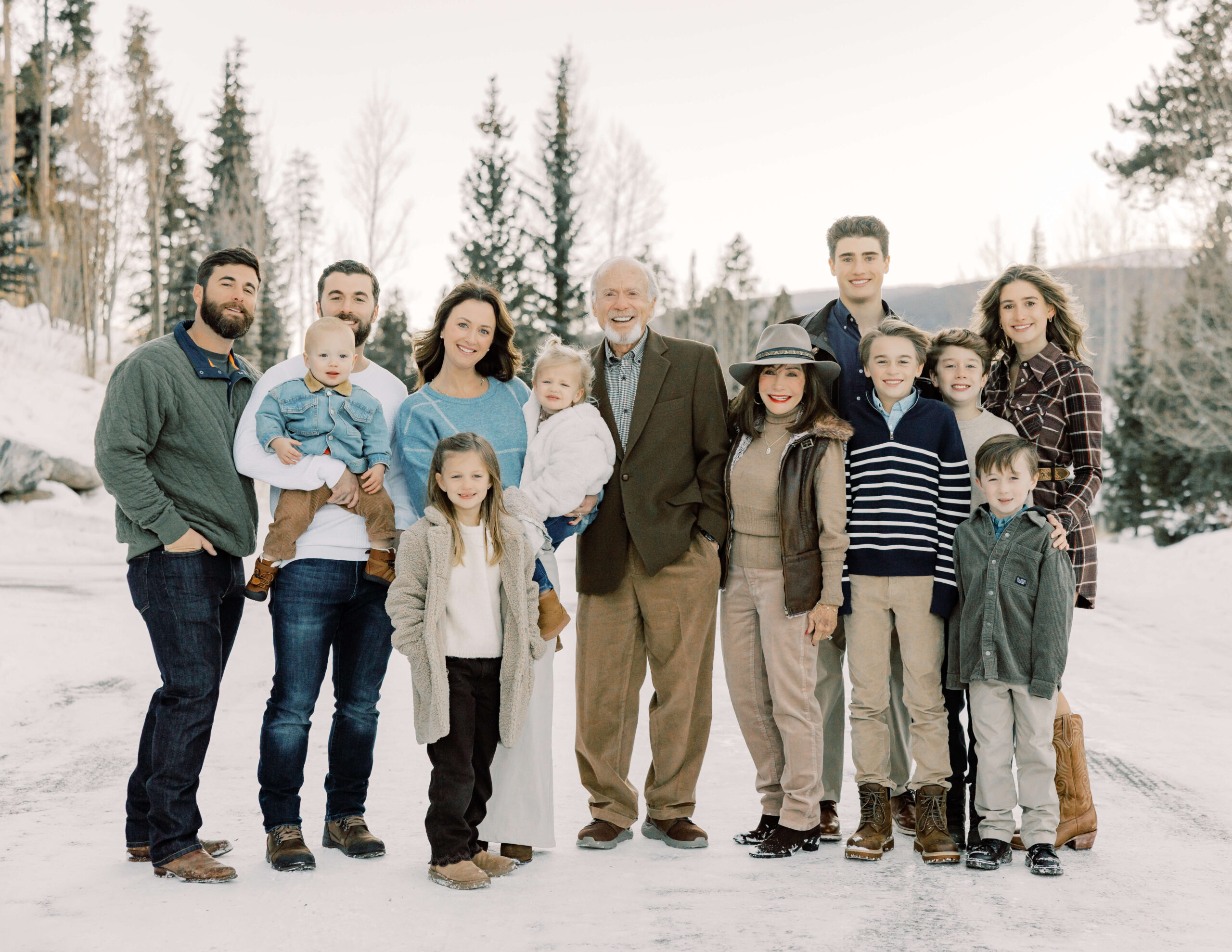 A happy extended family stands smiling in a snow covered path in the mountains before some Snow Tubing in Breckenridge