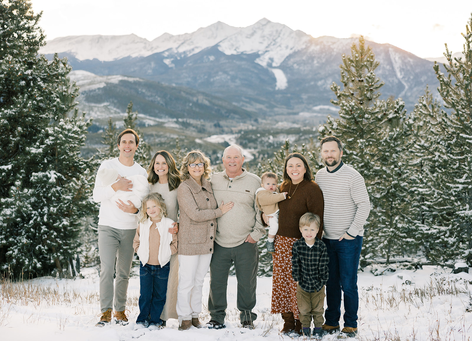 A happy extended family with four children stand on a mountain at sunset smiling in the snow at Breckenridge Fun Park