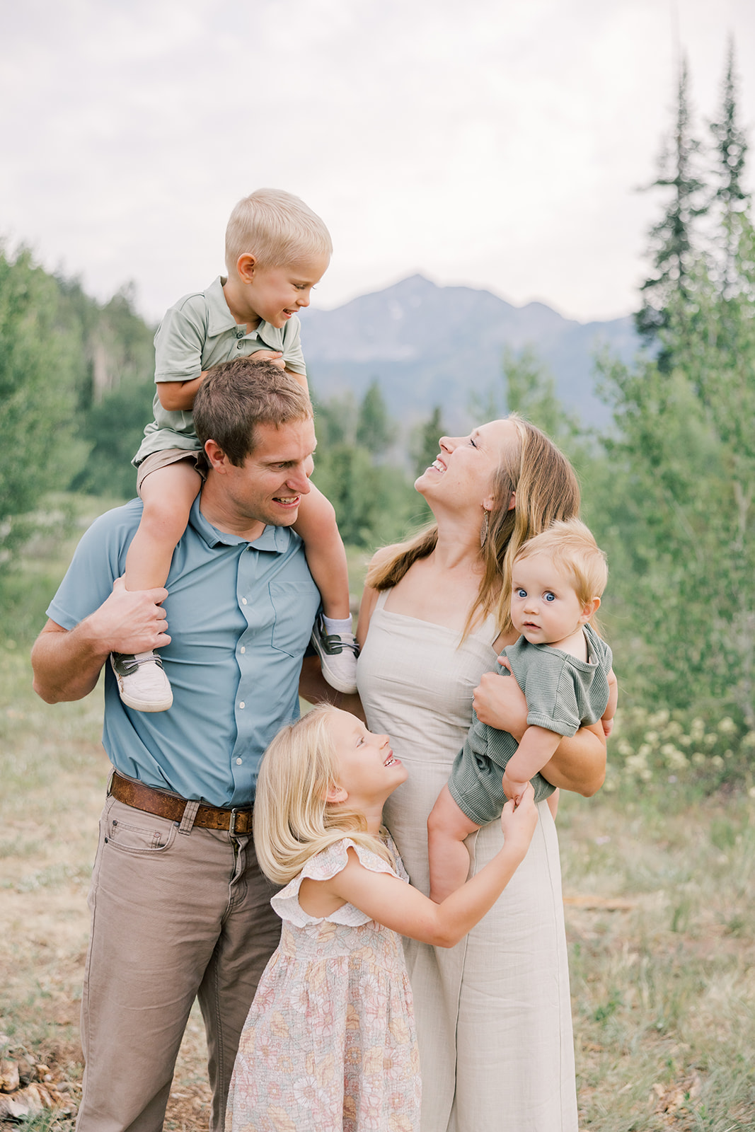 A happy family of five with 3 toddlers play in a park trail at sunset in the mountains after enjoying gold mine tours in Breckenridge