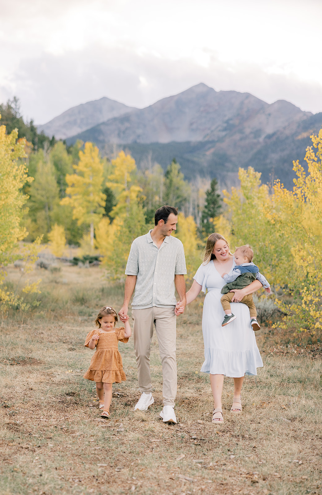 A mom and dad walk holding hands and their toddler son with daughter walking with them on one of the guided hikes in Breckenridge