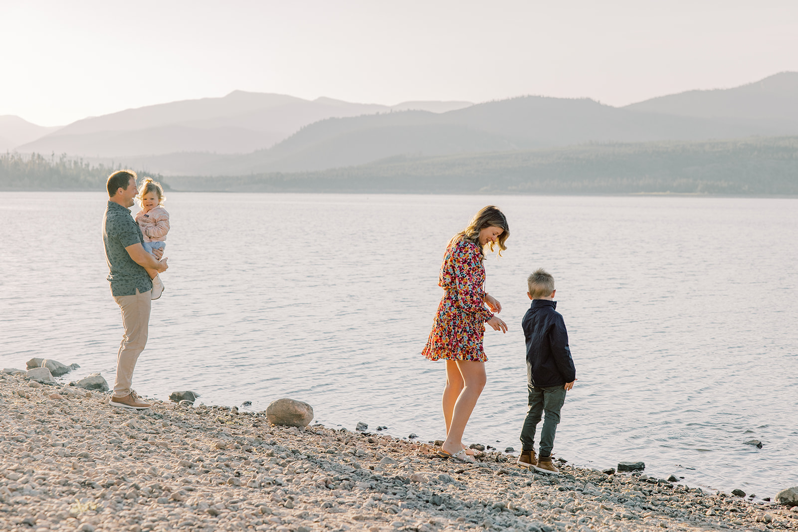 A mom and dad explore a lakeshore with their toddler sona nd daughter at sunset during one of the off-road tours in Breckenridge, CO