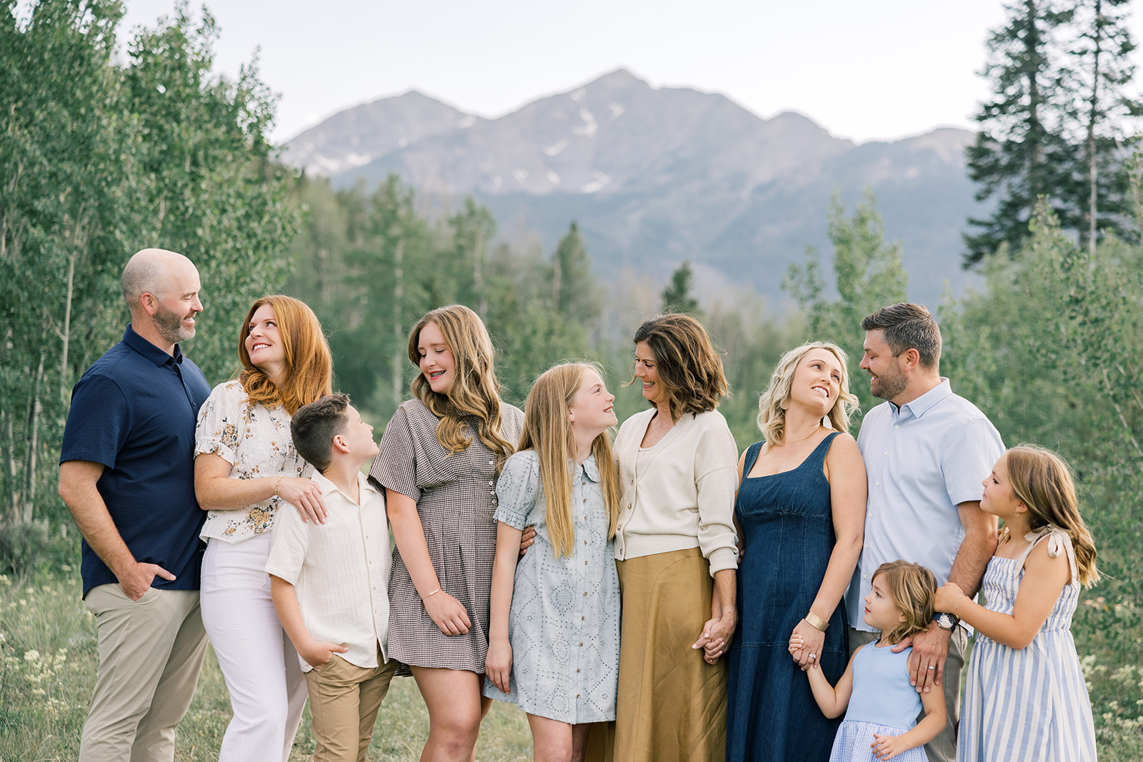 A happy extended family stand smiling at each other and holding hands in a mountain trail in spring