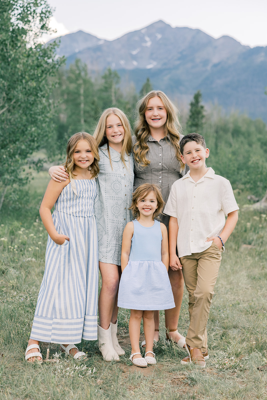 five siblings stand smiling in a trail in blue and tan while staying at Breckenridge family resorts