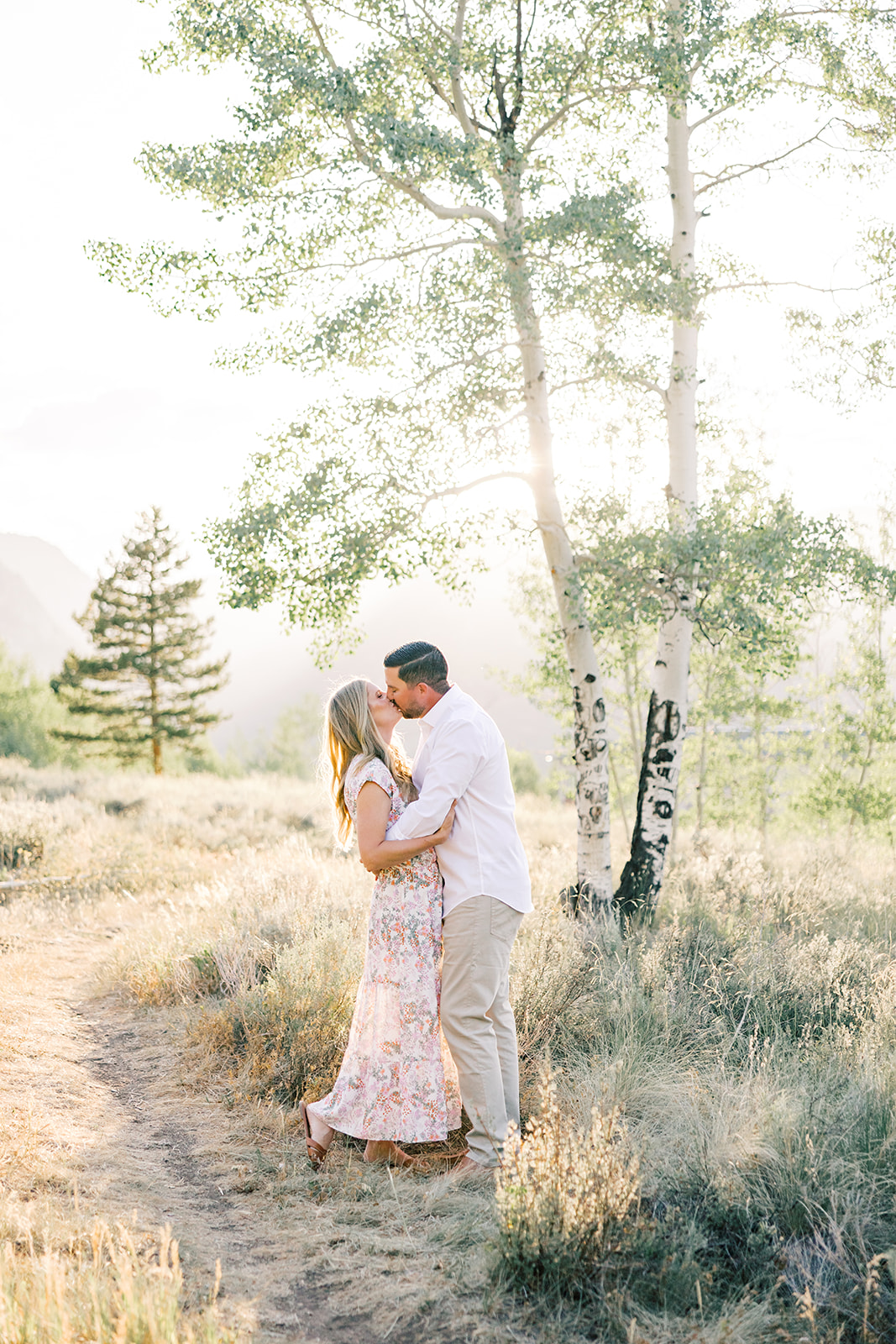 A happy couple kisses on a mountain trail at sunset while staying at a ski-in-ski-out in Breckenridge
