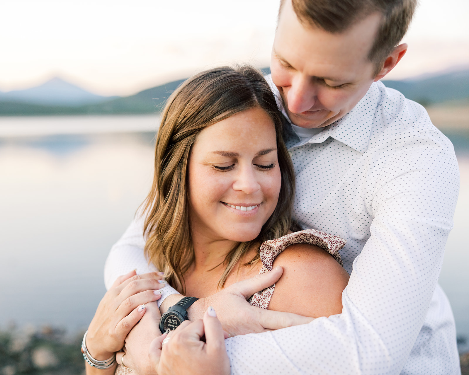A happy couple snuggles at sunset in the mountains