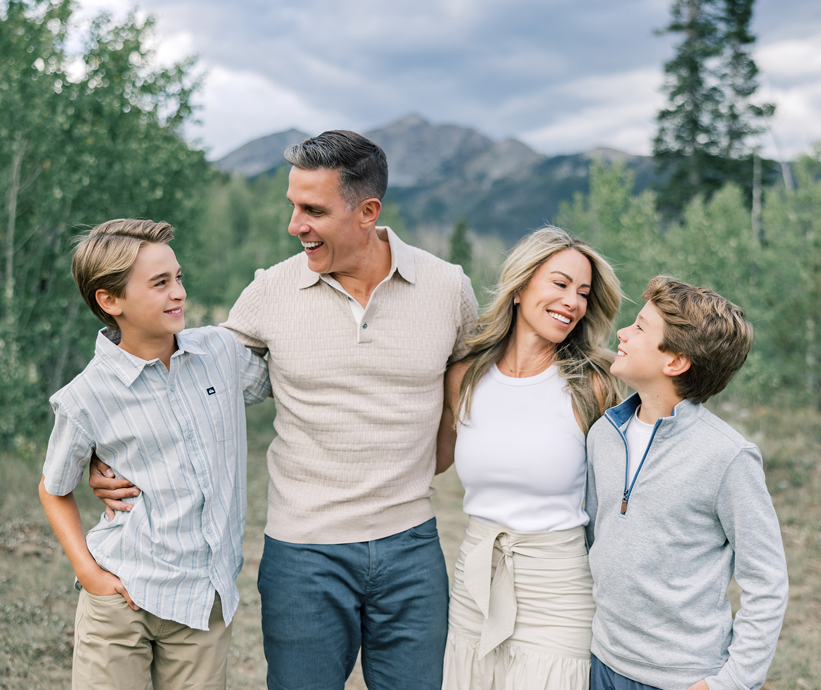 A happy family laughs with arms around each other in a mountain trail