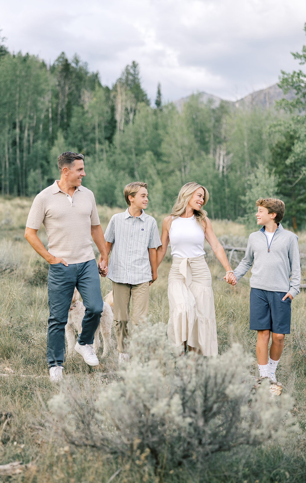 A happy family walks holding hands and smiling at each other in a mountain valley during one of the Breckenridge excursions
