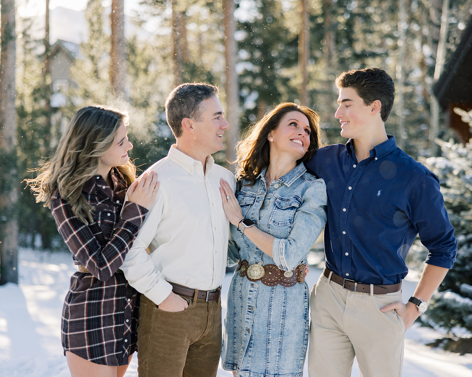 A mom and dad stand smiling in the snow with their teen son and daughter after some private ski lessons in Breckenridge